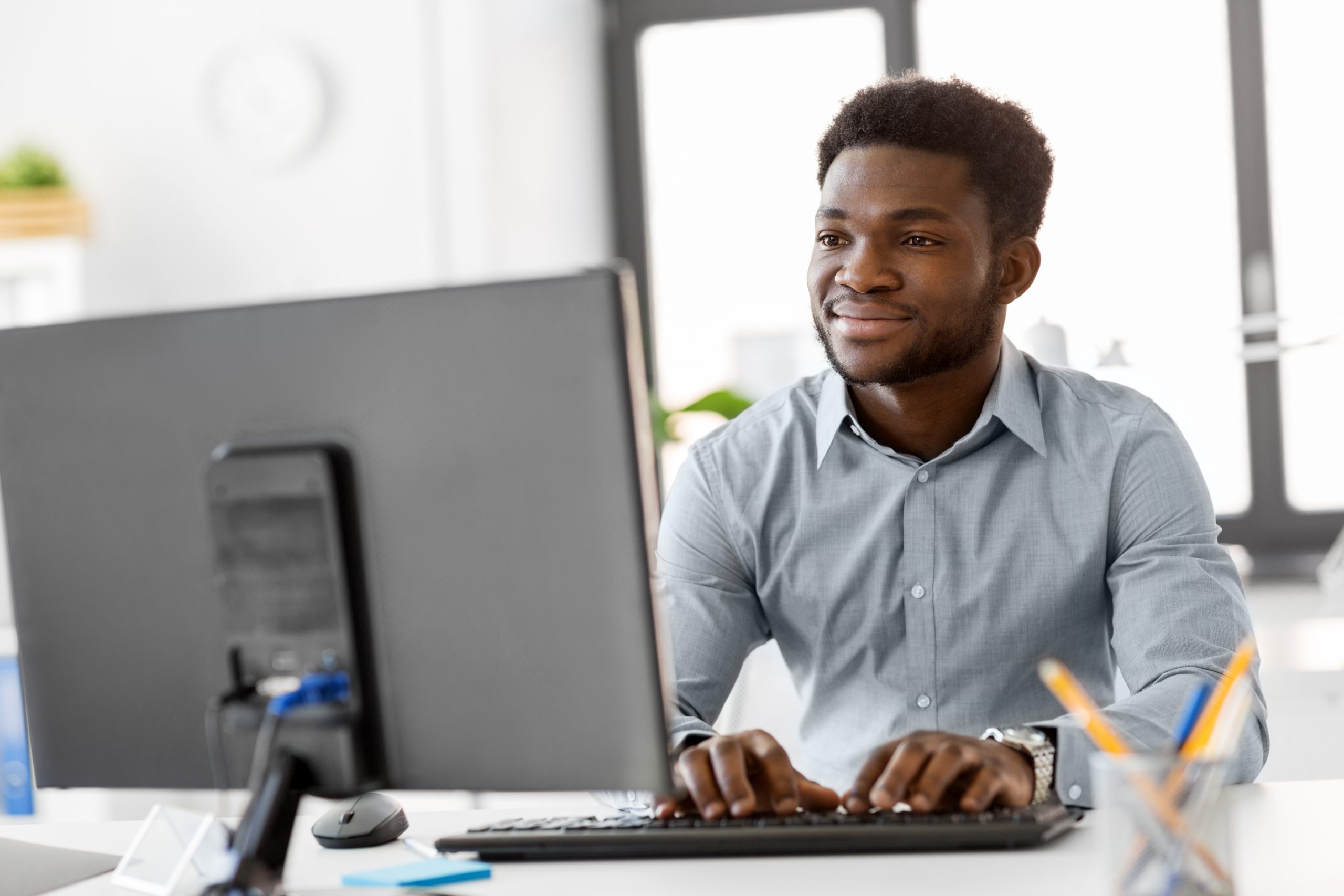 Smiling consultant typing at a desktop computer in a bright office