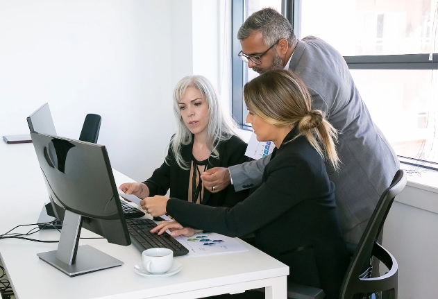 Three colleagues reviewing information together on a desktop computer
